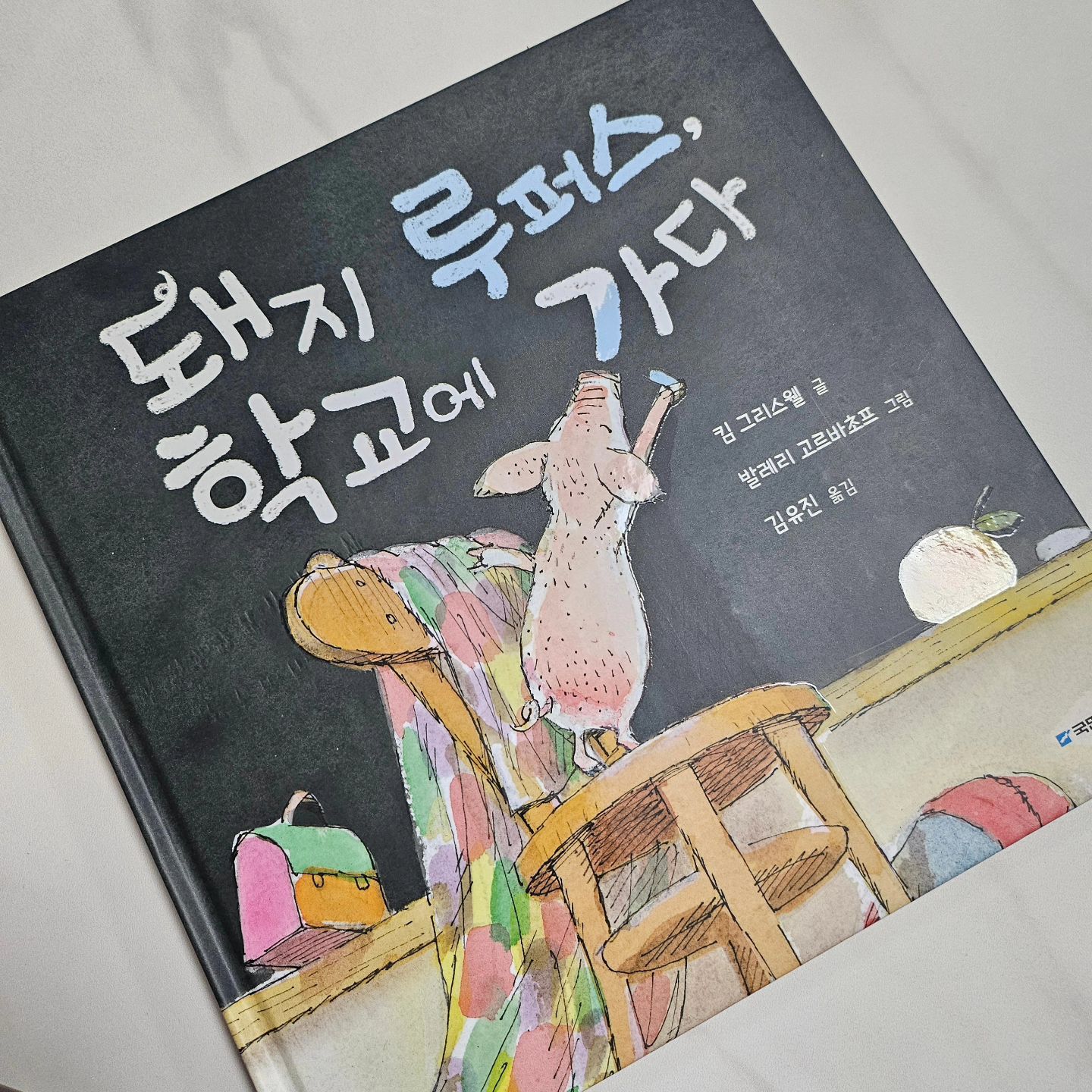 ⁣
자, 우리 어린이 친구들! 새로운 마음으로 시작한 새 학년, 새 교실에 적응은 다 했으려나? 아마 어느새 한 달이 된 지금, 설렘과 두려움은 익숙함과 친밀함으로 변했을 것이고 벌써 늦잠이 자고 싶어 아침에 일어나기 싫은 녀석들도 생겼을 것이다. 그런 우리에게 깜찍한 상상력과 즐거움을 주는 그림책, 『돼지 루퍼스, 학교에 가다』를 소개한다. ⁣
⁣
먼저 『돼지 루퍼스, 학교에 가다』는 그림책을 좀 본 사람이라면 너무나 익숙하다고 느낄지도 모르겠다. 그도 그럴 것이 우리의 루퍼스틑 바다도 가고 우주도 다녀오는 등, 꽤 유명한 녀석. 더불어 『돼지 루퍼스, 학교에 가다』를 그리신 발레리 고르바초프 작가님의 '난 뭐든지 셀 수 있어'나 '빨강 빨강 빨강' 역시 무척 유명한 그림책! 익숙함에 반가워 책장을 열면 작고 귀여운 돼지 루퍼스가 우리를 익살스럽게 맞이해준다. 책을 읽고, 책가방을 메고, 학교를 찾아가는 귀여운 돼지를 관찰하다 보면 웃음이 절로 난다. 다정하게 내려다보는 교장 선생님의 표정, 친구들과 장난을 치는 루퍼스를 바라보며 아이는 빙그레 미소짓기도 하고 깔깔 웃기도 한다. ⁣
⁣
『돼지 루퍼스, 학교에 가다』의 내용을 읽으면 그 웃음은 배가 된다. 학교에 다니고 싶어 용기 내 찾아온 루퍼스에게 거절하는 교장 선생님의 설명에 우리 아이는 살짝 속상해하기도 했는데, 창문에 코 자국도 남기지 않는다는 다짐에서 빵 터져버렸다. 그러더니 “이 정도의 장난꾸러기는 돼지 아니라도 수두룩하다고”하며 웃어버린다. ⁣
⁣
『돼지 루퍼스, 학교에 가다』를 읽고 아이와 대화를 나누며, “자 돼지도 가고 싶어 하는 학교에 가기 싫은가!”하고 물었다. 아이는 학교가 무척 가고 싶고, 재미있다고 말하며 이왕이면 루퍼스가 자기네 반으로 왔으면 좋겠다고 한다. 이제 꽤 많이 자랐지만, 여전히 그림책 속의 세상을 사랑하고 즐거워하는 아이. 우리 아이의 하루하루가 루퍼스의 학교생활처럼 즐겁고 행복하기를! ⁣
⁣
학교생활에 살짝 무료함을 느낀 친구가 있다면, 당장 『돼지 루퍼스, 학교에 가다』를 읽어 볼 것!