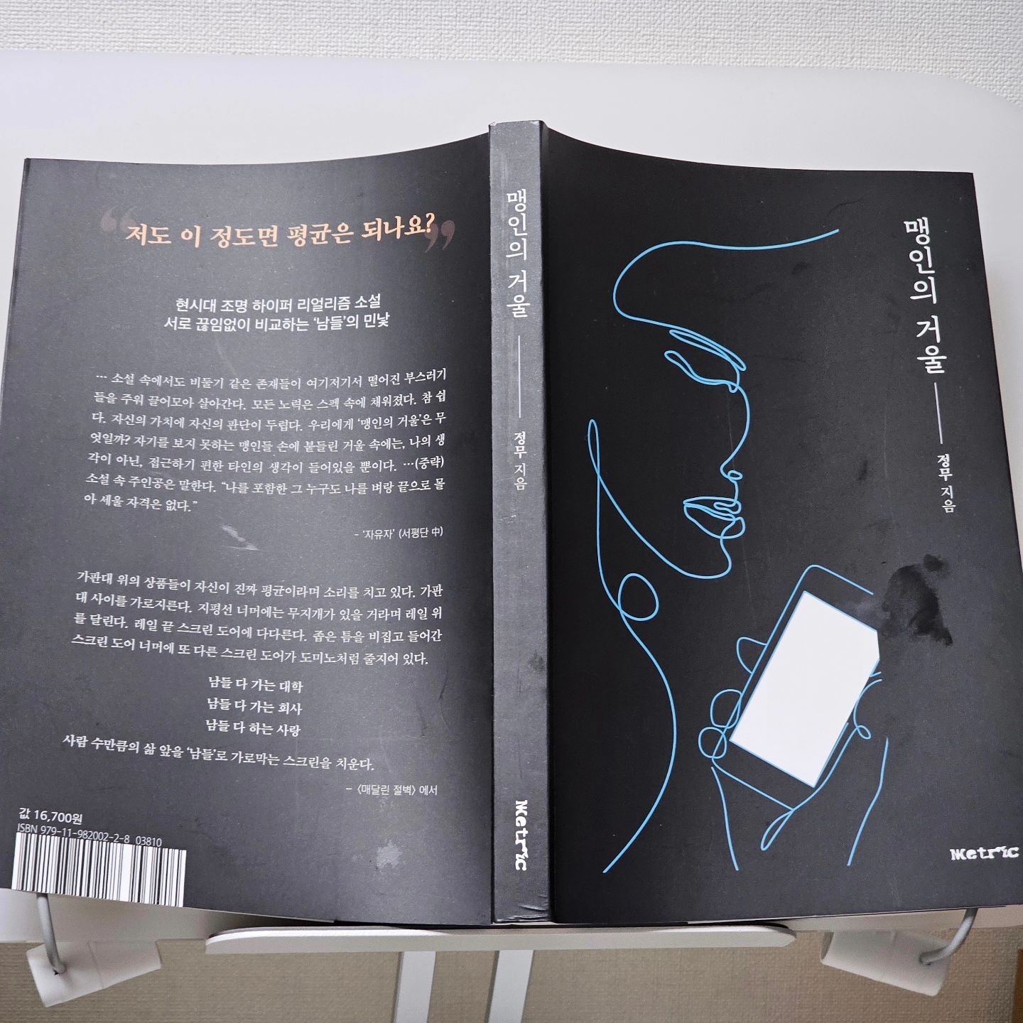 #협찬 #광고 #맹인의거울 #정무 #한국소설 #메트릭

만원의 엘리베이터 안에 한두 명은 더 탈 수 있지 않을까? 문이 닫히기 직전 대기업 P사 5년 차 대리 김영백이 엘리베이터 안으로 들어가면서 이야기는 시작한다. 그 엘리베이터를 불러 세우는 또 한 사람의 목소리가 들린다. 희망 가득한 눈을 엘리베이터를 마주한 그는 꽉 찬 엘리베이터 안을 보고 실망하면서 발걸음을 뒤로 물린다.

이렇게 시작한 이야기 맹인의 거울은 한국소설로 를 돌아보고, 아이들을 키우는 나의 인생책이 되어 버렸다.

메트릭에서 출간한 정무님의 소설 맹인의 거울은 우리의 모습을 너무 잘 보여준 이야기이자, 누구나 공감 가면서 재미를 느낄 수 있는 그런 이야기다. 그러나 그 재미속에 불안감도 내포되어 있다.

직장인 생활을 접은 지 십 년이 넘은 나지만, 맹인의 거울 첫 장면을 보면서 회사를 다니던 그 사절이 참 그리워진다. 어찌 보면 돌아가는 쳇바퀴, 너무 치열하게 살아가는 사람들, 그리고 하루하루를 보내는 직장인의 이야기를 보면서 왜 나는 그 시절이 그리워지지?

가지지 못한 것에 대한 애절함일까? 누군가의 아내와 엄마로만 살아가고 있는 지금이라 그럴까?

#한국소설 맹인의 거울의 첫 장면 직장인들의 퇴근 무렵의 모습을 보면서 동질감을 많이 느낄 거 같다. 그러나 소설을 계속 읽어갈 수록 왜 지금 내 삶이 다행이다는 생각이 드는건지 모르겠다.. ㅜㅜ 너무 이기적인건가?

결국 이야기를 읽어 갈수록 희망과 즐거움으로 엮인 소설은 아니라는 걸 알게 되었기 때문일 것이다. 이 시대를 살고 있는 현대인들의 모습을 적나라하게 묘사하고 있다. 맹인의 거울. 과연 그 속엔 무엇이 있을까?

서로가 서로를 비교하고, 날 알지도 못하는 사람에게 스펙으로 평가받고, 내 인생을 타인에게 묻고... 그들은 그렇게 나를 알지도 못하도 못하고 나를 평가한다. 맹인의 거울처럼.

맹인의 거울에 지배당하지 말자. 나는 나다. 그들은 나를 모른다. 나를 평가할 이유도 없고 그 속에서 나를 찾을 필요도 없다.

지금 이 책을 보면 난 참 좋은 시대에 살았다는 생각이 든다. 내가 젊었을 그때보다 지금은 더 살기 좋고, 사람들의 스펙은 더 좋기만 하다. 그런데 모든 사람들이 그렇다는 것이 문제가 되는 세상. 정말 잘 났고 많은 것을 알고 있음에도 이 시대를 살아가는 것이 어렵겠다고 느낀다. 그리고 이 세상을 살아갈 나의 아이들의 미래가 많이 걱정되기도 했고, 불안하기도 하다. 그러나 알아서 살아가겠지 했지만, 이 책을 보면서 느낀다. 스스로의 멘탈이 엄청 중요하겠다는 것을 말이다.

지금 이 시대에 #베스트셀러가 될 수 밖에 없는 내용을 담고 있다. 왜냐하면 진짜 한국소설이라고 밖에 말할 수 없는 지금 이 시대를 살고 있는 이들의 모습이니까.

학벌, 외모, 집안, 자산 그런 것들로 나를 알지도 못하는 이들로부터 평가를 받지 말자. 처음 들어가는 이야기를 보면서 재미있겠다 했지만 정말 너무 현실적이라 이게 소설이 맞나 하는 생각을 가졌던 이야기다. 허구라 하지만 허구 같지 않은 이야기가 마음을 좀 답답하게 만든다. 이 책을 읽으며 미래를 꿈꾸는 이들이 바른 가치관을 갖길 바란다.

#소설 #인생책 #소설추천