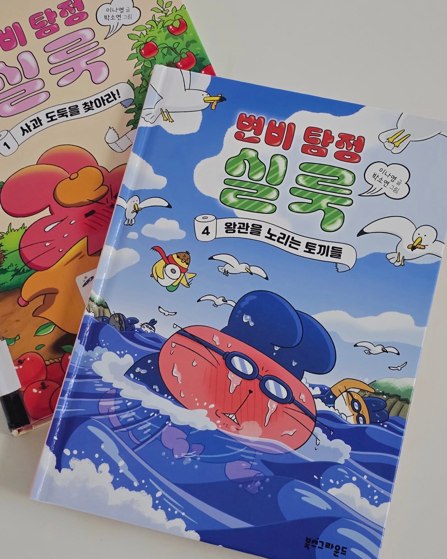 #서평 #책추천 booksground
은찬이가 너무 재미있게 읽고 있는 책 📚✨
제목부터 웃긴 《변비 탐정 실룩》....🤣 

이번에 4권 왕관을 노리는 토끼들 신간이 나왔는데요!
변비 걸린 탐정 실룩이 너무 귀엽고,
엉뚱하지만 똑똑한 문제 해결 방식에
저도 같이 읽다 푹 빠져버렸어요ㅎㅎ🐰🤍

평소에는 느긋하게 걷는 걸 좋아하는 실룩,
하지만 이번에는 다르게! 🏃‍♂️💨
'강토끼 3종 경기 대회'에 참가하면서 뛰고, 헤엄치고,
자전거 타는 실룩을 보게 될 줄은 몰랐어요ㅋㅋ

그리고, 명탐정 실룩답게, 사건도 빠질 수 없죠!
‘강토끼 3종 경기 대회’에서
1등에게 주어지는 귀한 황금 왕관이 👑
행사장으로 가는 배 안에서 사라졌는데요!

과연 범인은 누구일까?🧐
밀실 사건인 만큼, 실룩의 활약이 더욱 기대돼요ㅎㅎ
실룩의 추리와 수사 현장을 따라가면
아이가 스스로 풀어볼 수 있는 미션도 있어서
초집중해서 앉은 자리에서 한 권 뚝딱 읽어요
《변비 탐정 실룩》, 아이와 함께 재미있게 읽었습니다🫶

#북스그라운드 #변비탐정실룩
#명탐정실룩 #토끼탐정
#추리동화 #왕관을노리는토끼들
#문고판추천 #저학년책추천
