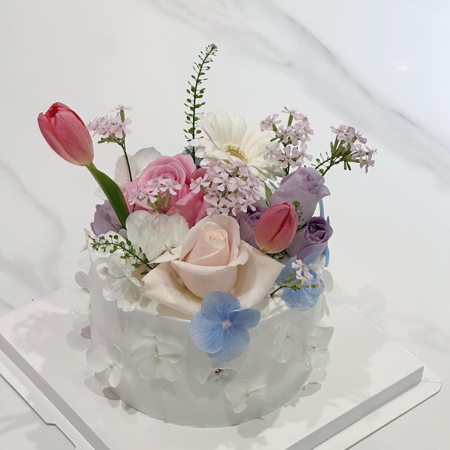 감성터지는 비주얼의 revoir_flowerstudio
꽃과 케이크를 함께 준비할 수 있고,
그대로 그림을 옮겨온 것 같은 #생화케이크 를 만날 수 있는 곳✨

🗝우유생크림에 바닐라시트, 모두 직접 만들어요.
🗝첨가제와 보존제를 사용하지 않아요.
🗝원하는 컬러감을 지정할 수 있어요.

어느덧 365일, 잘 버텨왔다는 의미를 더하려고 주문했는데
한 폭의 그림을 픽업해오는 기분이었어요.
조화는 따라올 수 없는 생화의 매력은 어쩔 수 없구나 싶었던.

폭신한 시트와 묵직하면서도 부드러운 크림,
시트 안을 알알이 장식한 샤인머스캣이 톡 터지는 맛까지😆

어른들도 좋아하실 것 같고,
브라이덜 샤워 케이크로도 너무 좋을 것 같았던🪄

📌부산 부산진구 서전로68번길 103 2층
.
.
.
#부산생화케이크 #전포동케이크 #서면케이크 #부산케이크 #서면생화케이크 #서면꽃집 #전포동꽃집