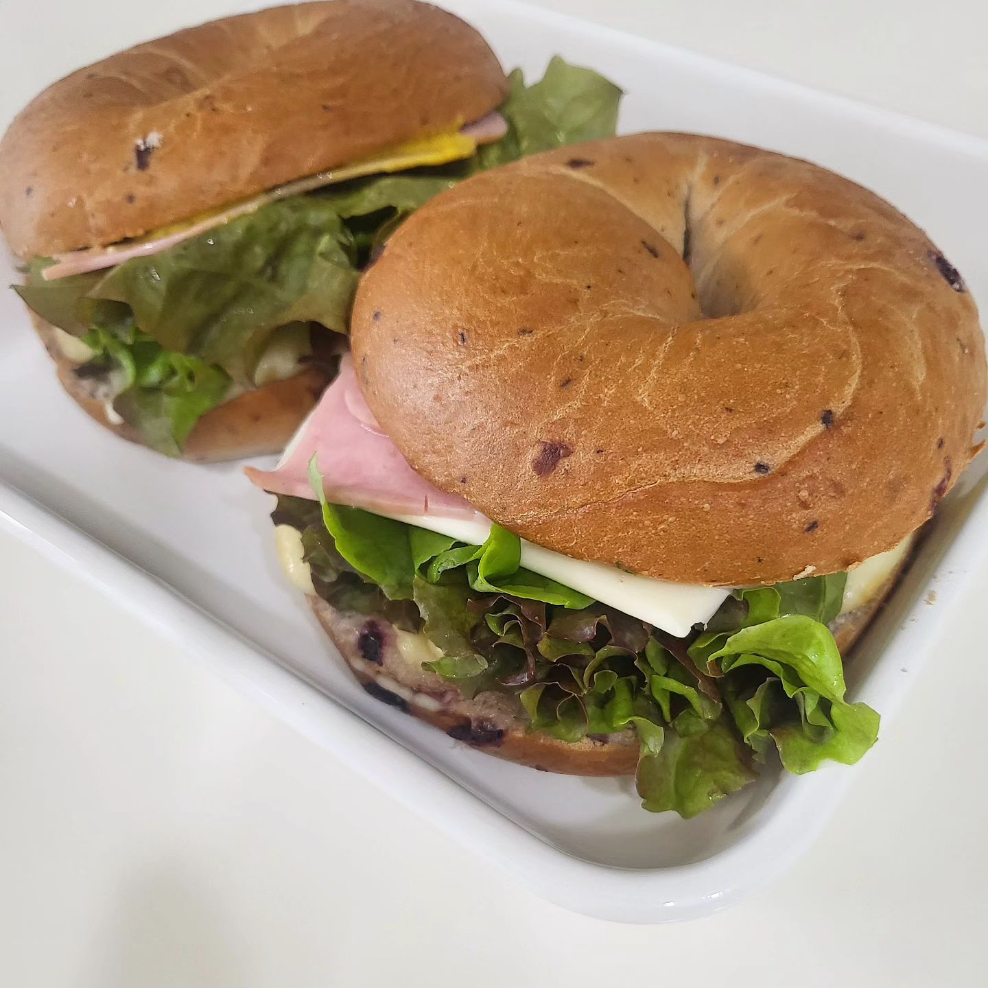 지난 일요일,모닝 베이글 샌드위치🥯
(역시나)새벽 같이 일어난 아드님 덕분에 엄마아빠도 부지런 떨었지요😆

유누는 계란스크럼블해서(+야채볼) 맛간장+참기름 넣어 비벼주고
엄마아빠는 냉동실 베이글 꺼내 샌디치 호다닥 만들었어요!

🥯베이글샌드위치
-베이글 한쪽에 바질페스토 바르고 페퍼잭치즈 올려 에프에 녹이고
-다른 한쪽 갈릭마요만 살짝 발라 에프에 살짝 굽굽한 다음
-그다음 머스타드 바르고 그위에 샌드위치 햄(뜨거운 물에 데침)두장씩
 올리고 야채도 올리고(사실 전날 먹고남은 상추ㅋㅋㅋ) 베이글 덮으면 
끝!( 신랑은 슬라이스치즈 하나 더 추가해드림🧀)
-토마토도 넣고팠지만 귀찮아서 패스...

바질페스토가 정말 샌드위치의 킥!!인지 진짜 너무 맛있었어요😭
그리고 페퍼잭치즈도 녹이니 너무너무 맛잇고 매콤하고 진짜
아주아주 너무 잘어울렷어여...이렇게 또 해먹을 의향 1000%🥹🥹

#홈브런치
#샌드위치
#베이글샌드위치
